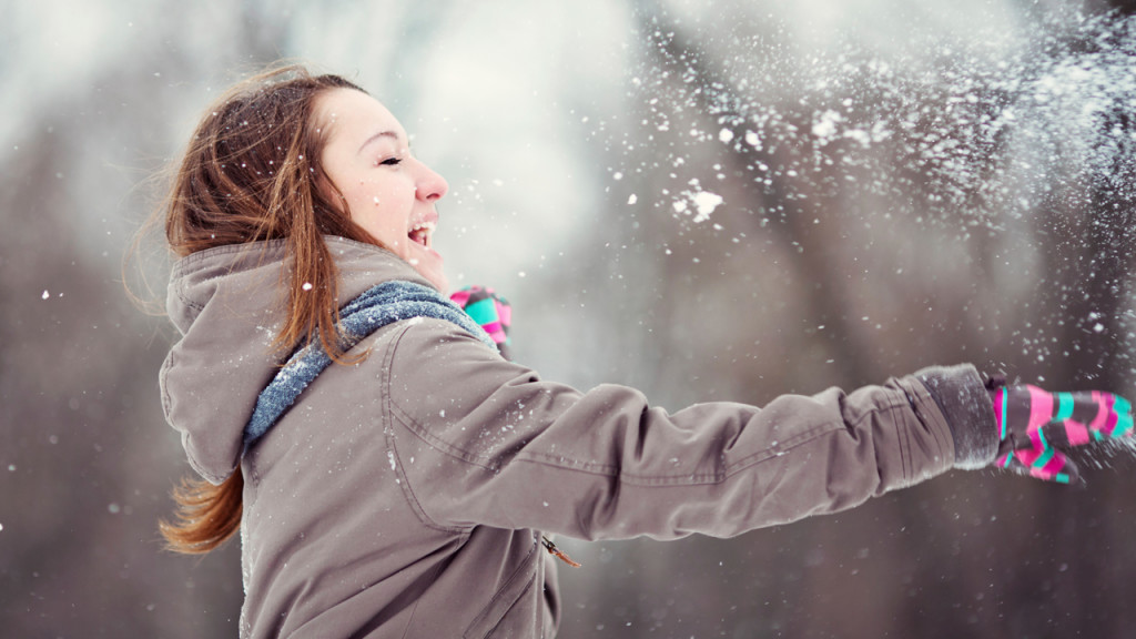 Image of woman throwing snow up in the air during a winter day